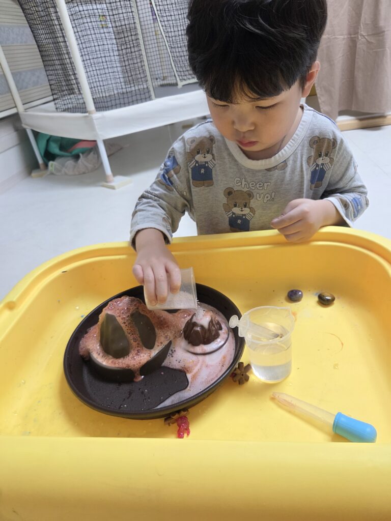 붉은색 색소와 주방세제가 섞인 용암 거품이 화산 모형 밖으로 솟구쳐 오르는 화산폭발 실험 장면