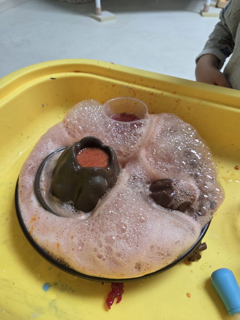 5세 아이가 집에서 베이킹소다와 구연산을 이용해 화산폭발 실험을 하며 화학 반응을 신기하게 관찰하는 모습